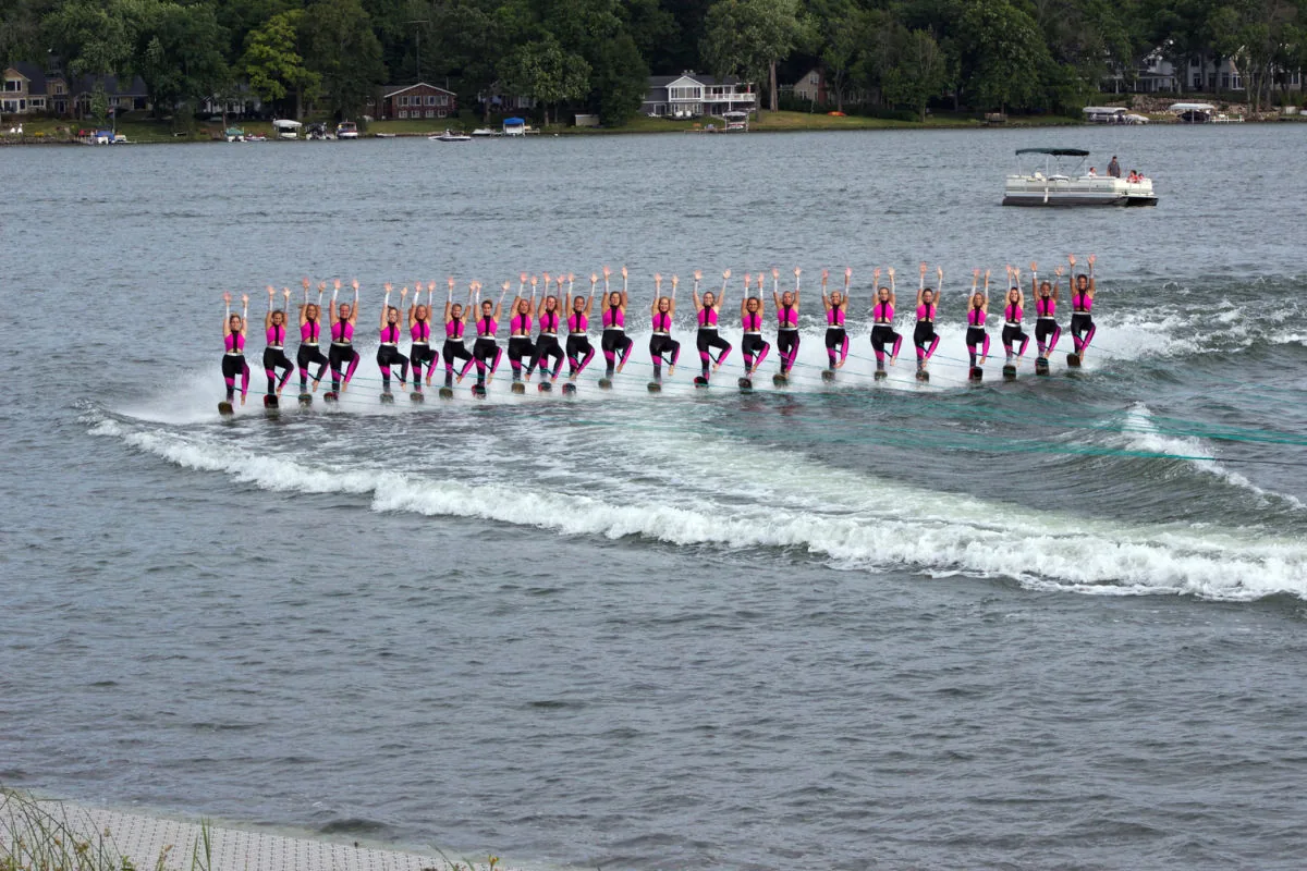 Synchronized water ski team on Twin Lakes with a wooded, home-lined shore behind